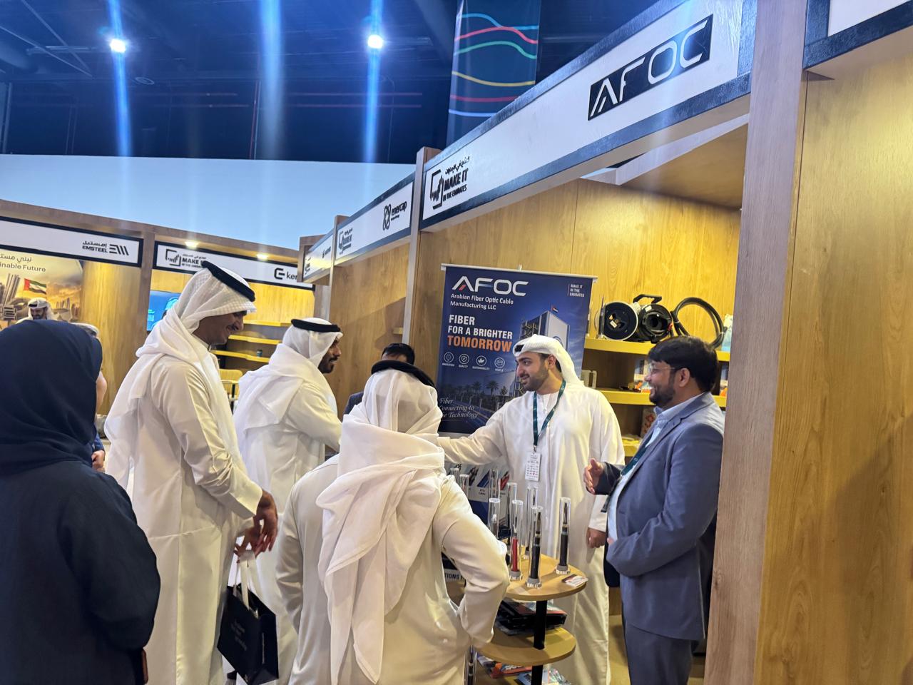 AFOC representatives welcoming visitors at the stand beside the Fiber for a Brighter Tomorrow banner